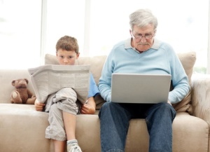 Boy reads newspaper gramp on laptop